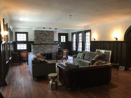 interior of historic house with wood floor, fireplace, white walls, and couches