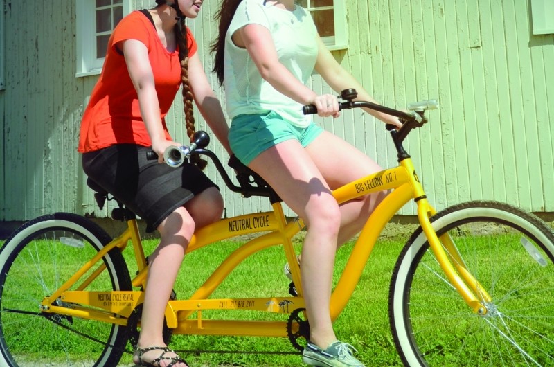 People riding on a yellow tandem bike.