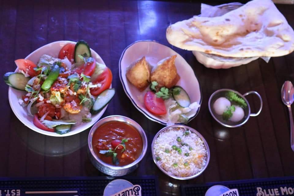 Variety of Indian dishes including rice, samosas, curry, and salad