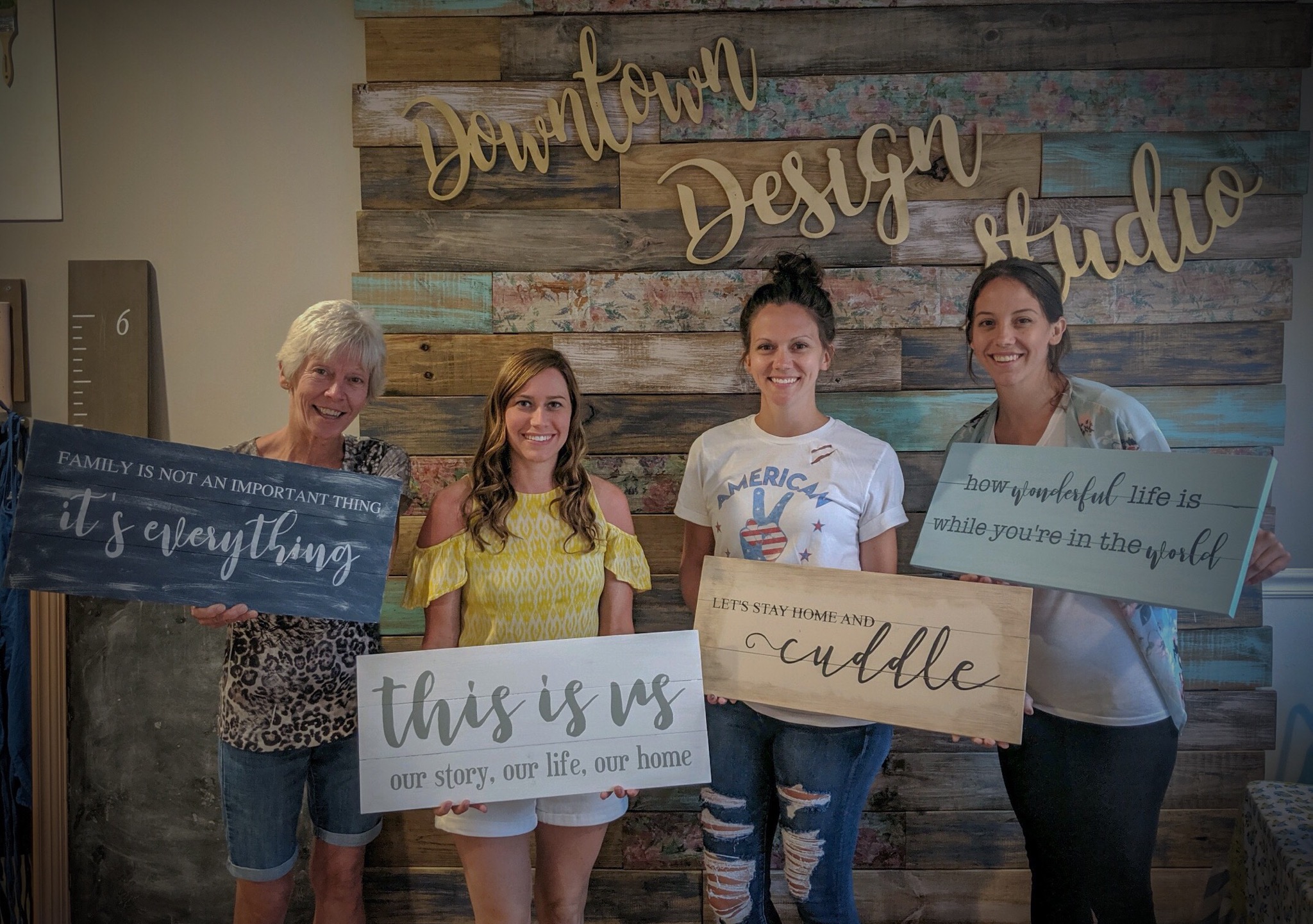 Happy customers at Downtown Design Studio holding signs they made.