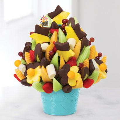 Edible arrangement featuring different fruits and chocolate covered pineapples.