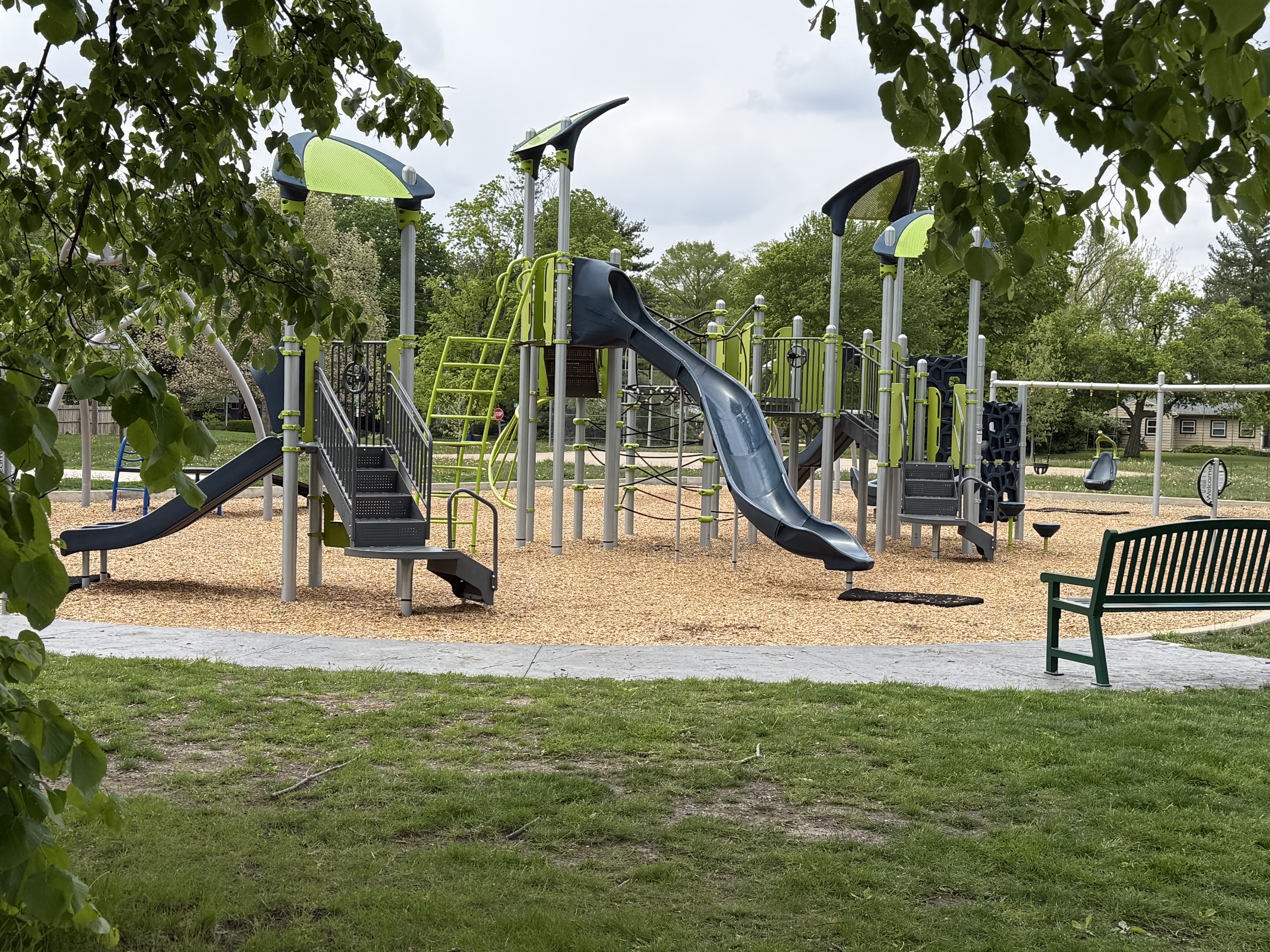 blue and green playground with woodchips and grass