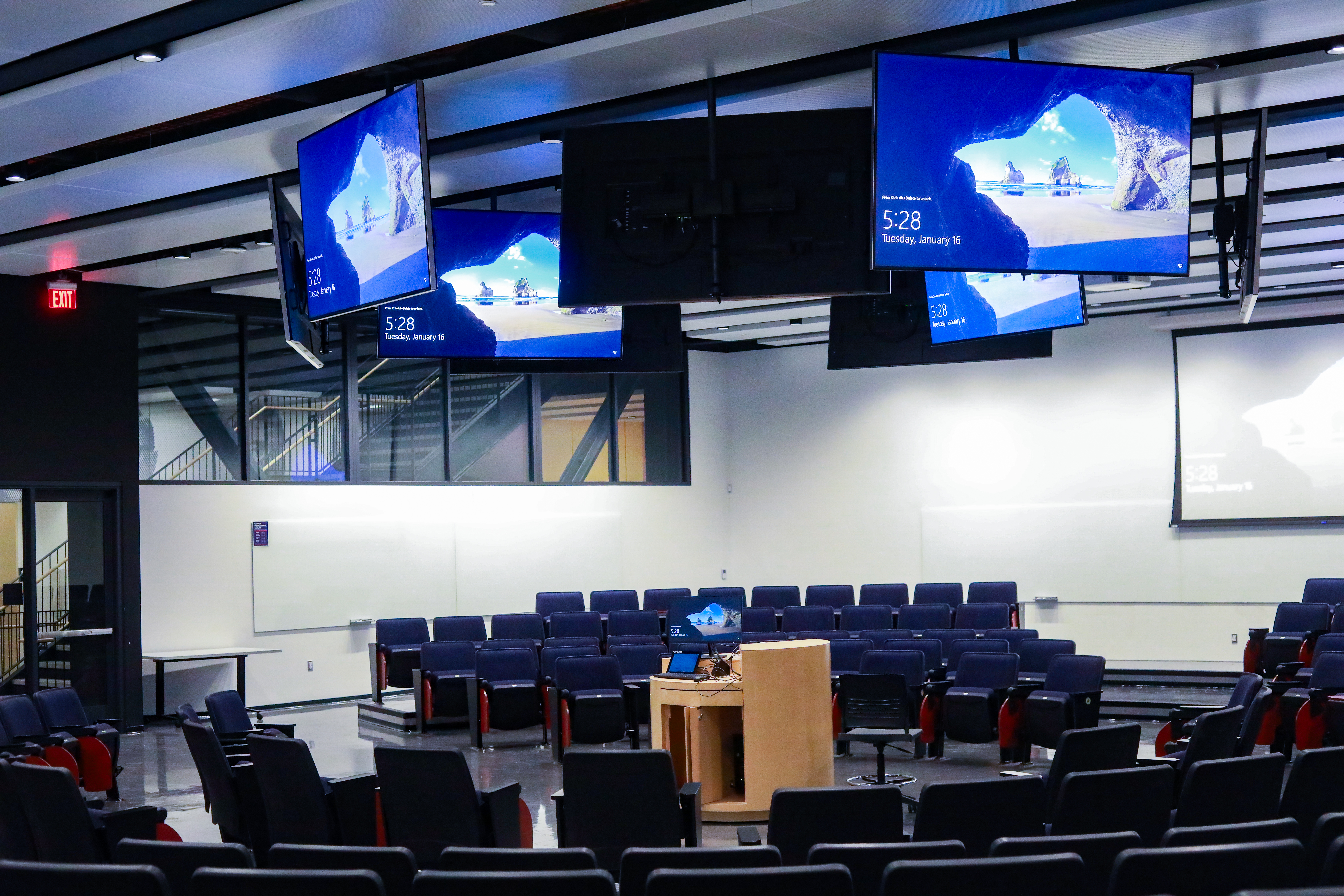 Classroom with seats arranged in a circle and large tv monitors
