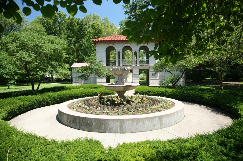 Stone plant bed with stone structure behind, surrounded by trees