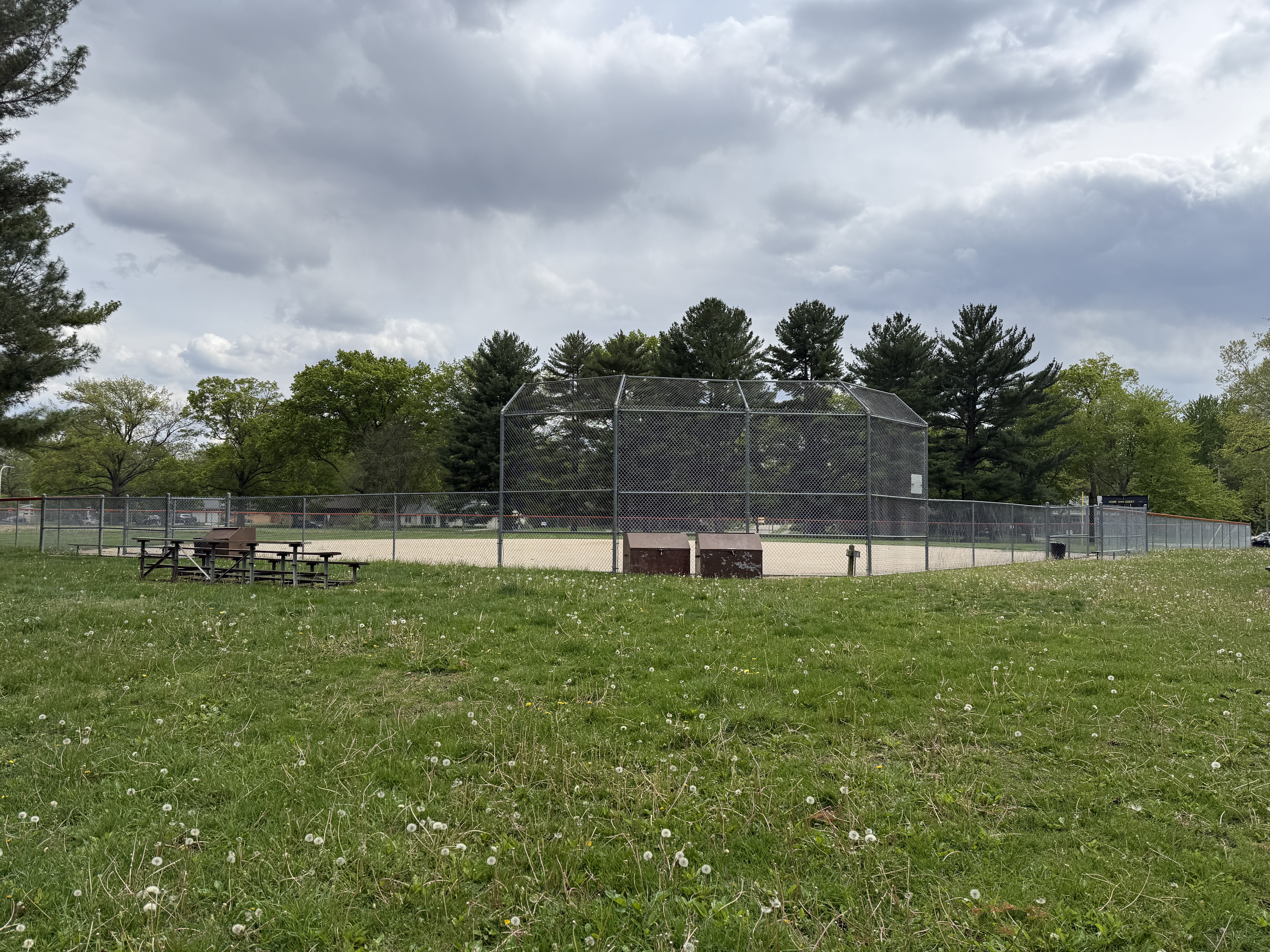 Sandy baseball diamond with a chain link fence and grass behind