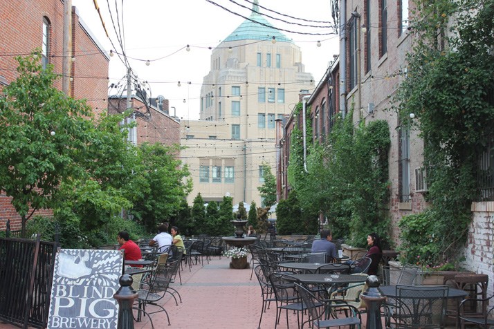 outdoor beer garden with a brick ground, chairs, and background city building