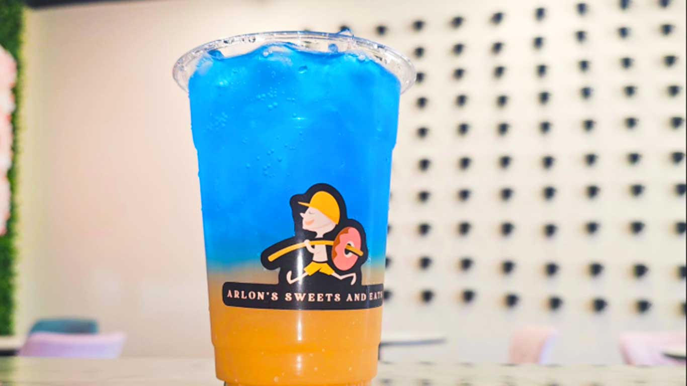Iced blue-and-orange drink in plastic cup on table