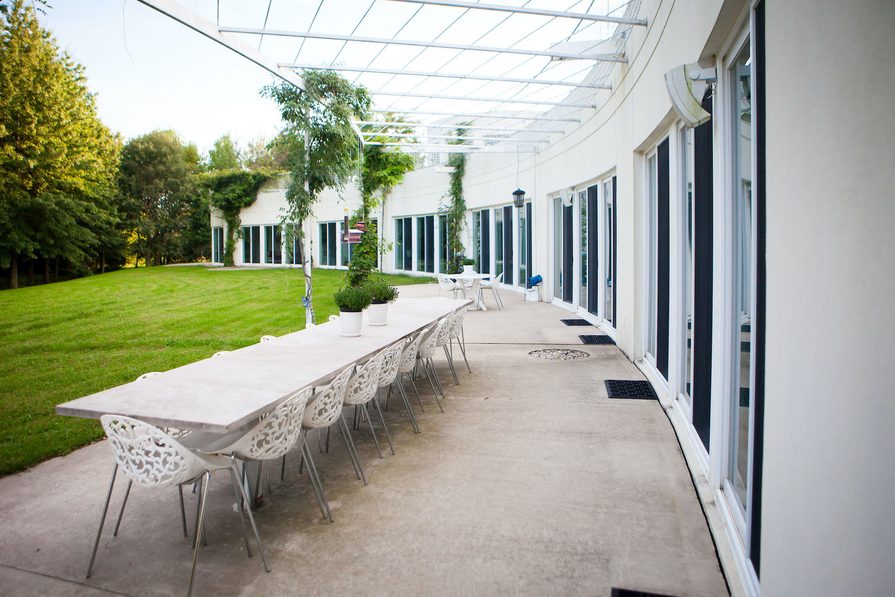 Exterior wall of a long white structure with many windows next to a long, white table