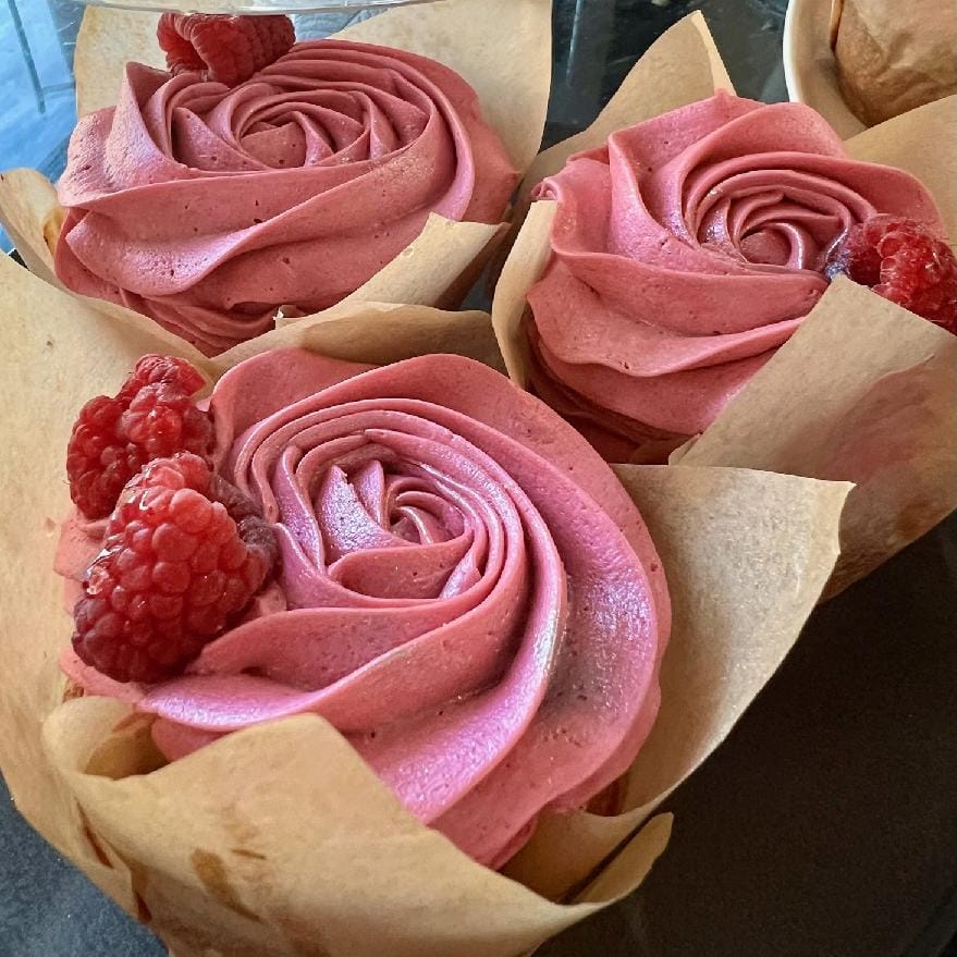 Cupcakes from Lucky Moon Pies decorated with frosting that looks like a rose and raspberries.