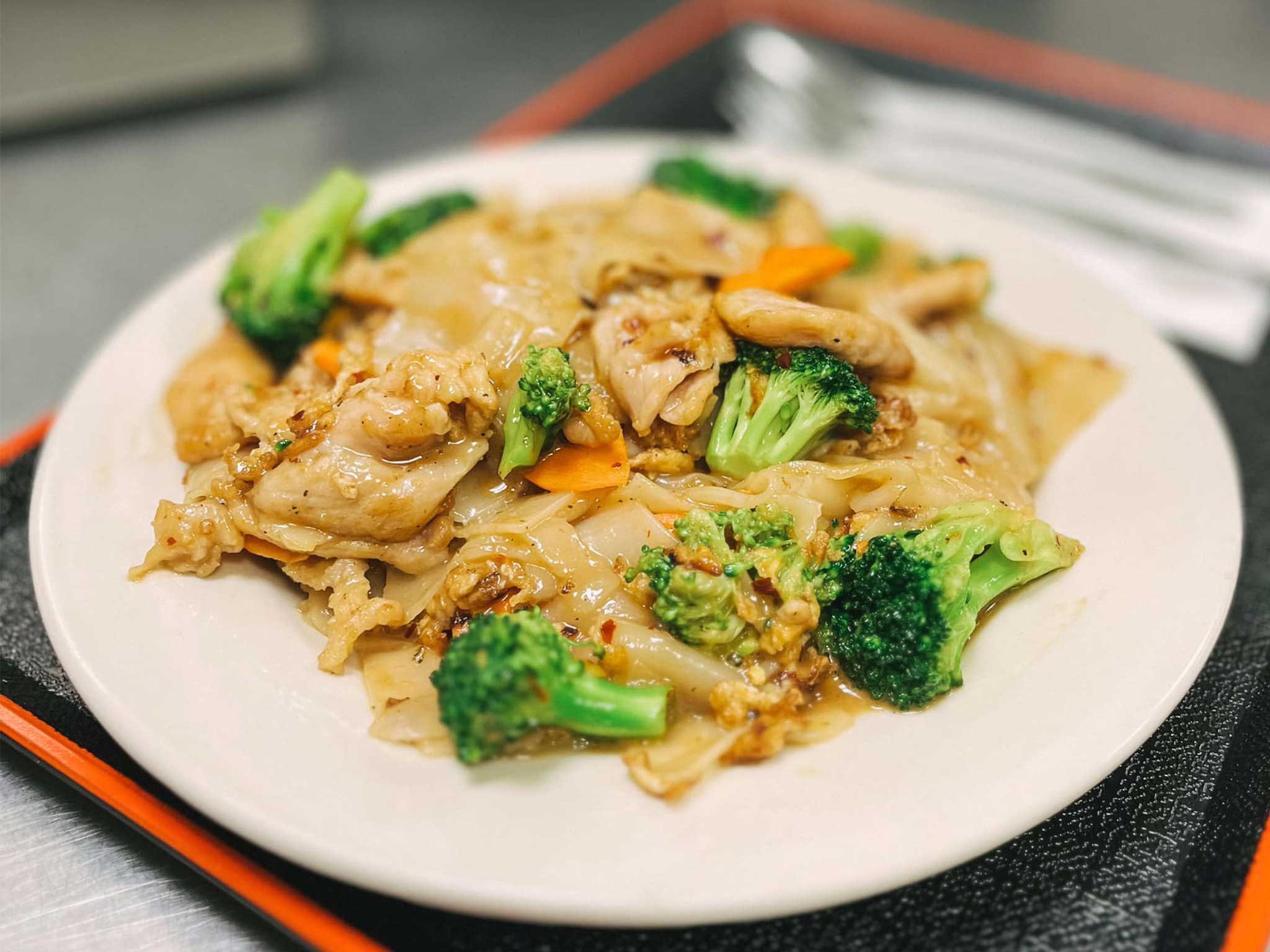 Plate of pad see ew, a spicy thai dish, with chicken, broccoli, and carrots