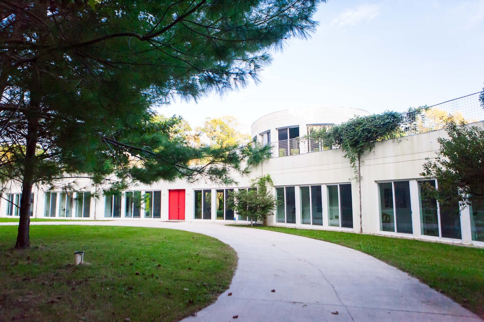Long, white structure with many windows and a red door
