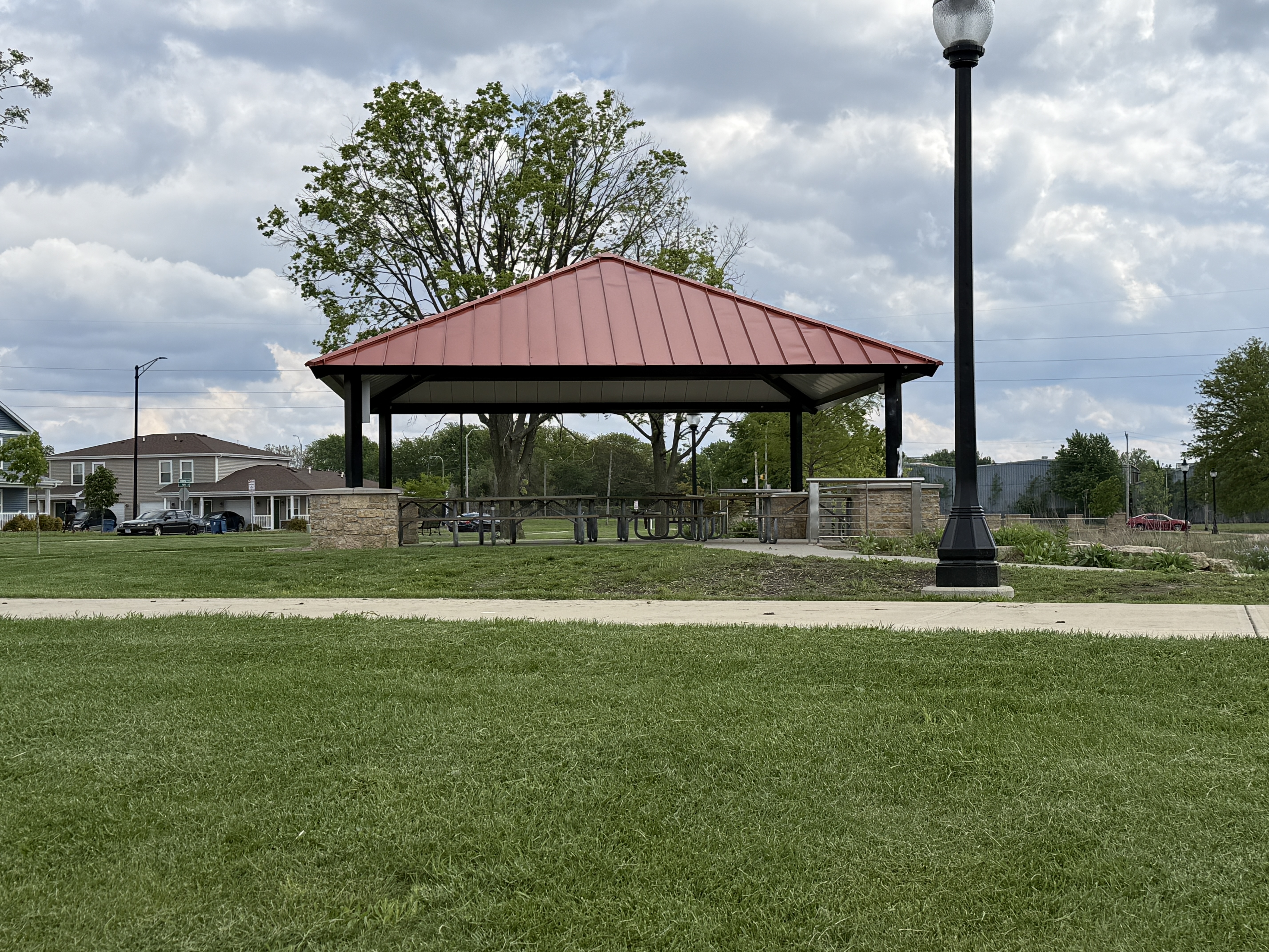 pavilion with a copper roof, tables, behind grass and a walking path