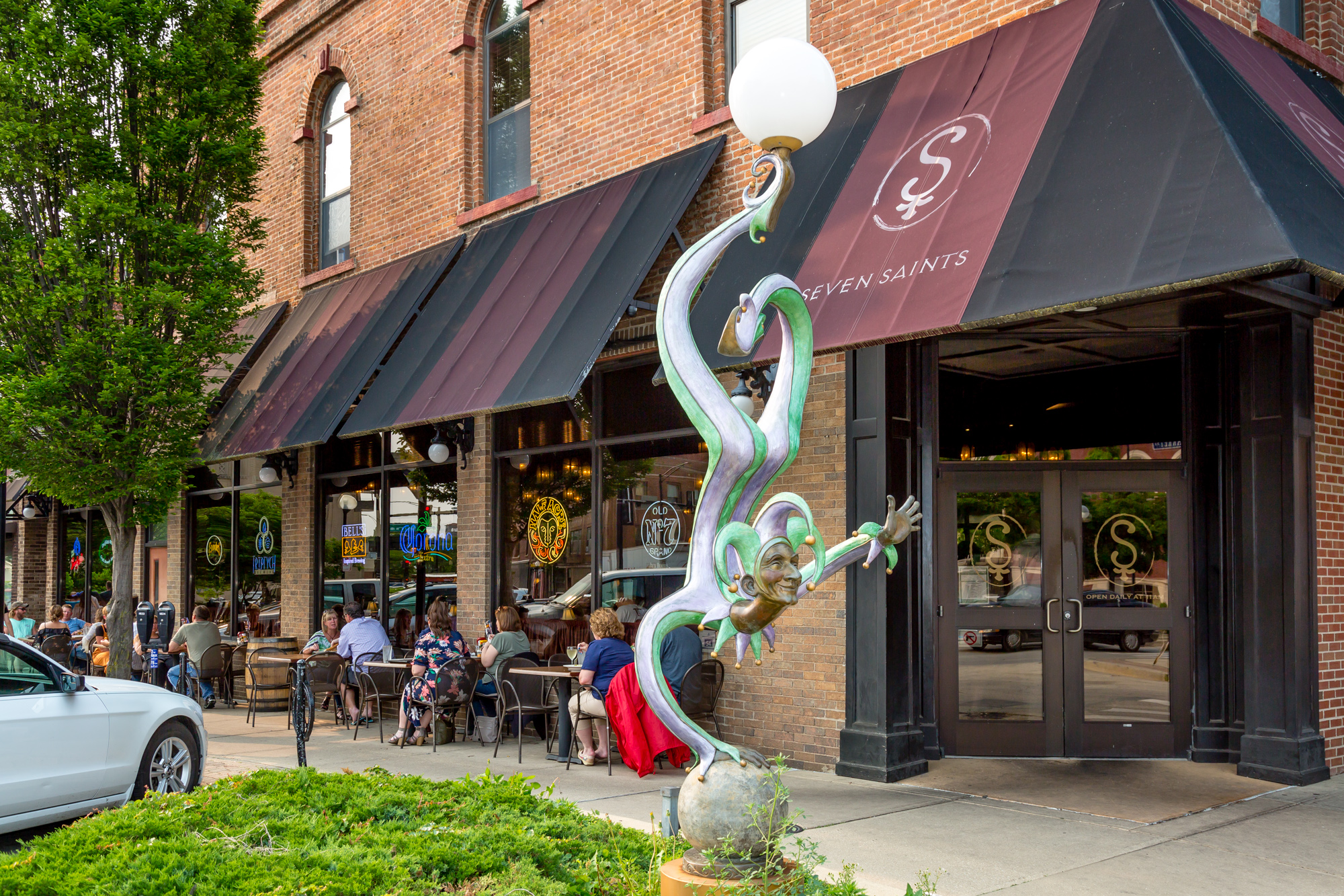 brick restaurant with outdoor seating, a canopy, and a clown statue