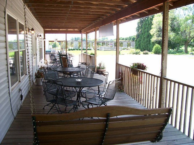 covered patio with black metal tables and a swinging bench