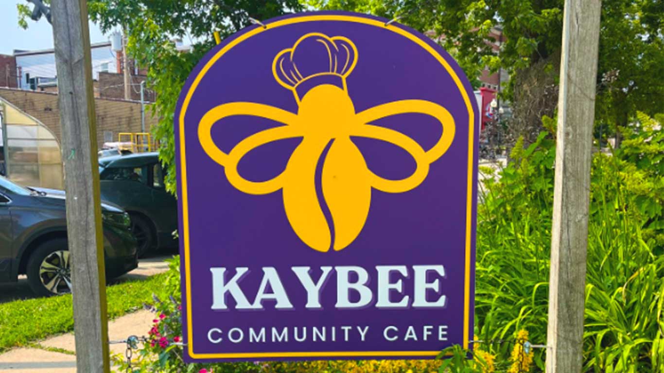 Outside café signage, featuring a yellow bee on a purple background