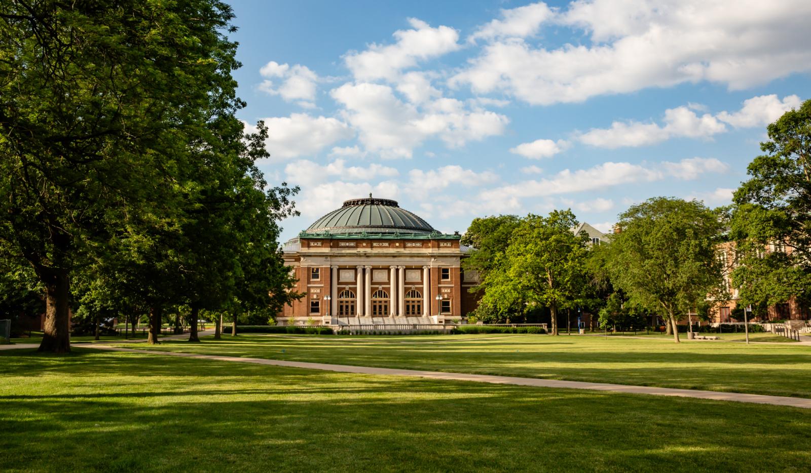green space surrounded by trees with a brick building in the background