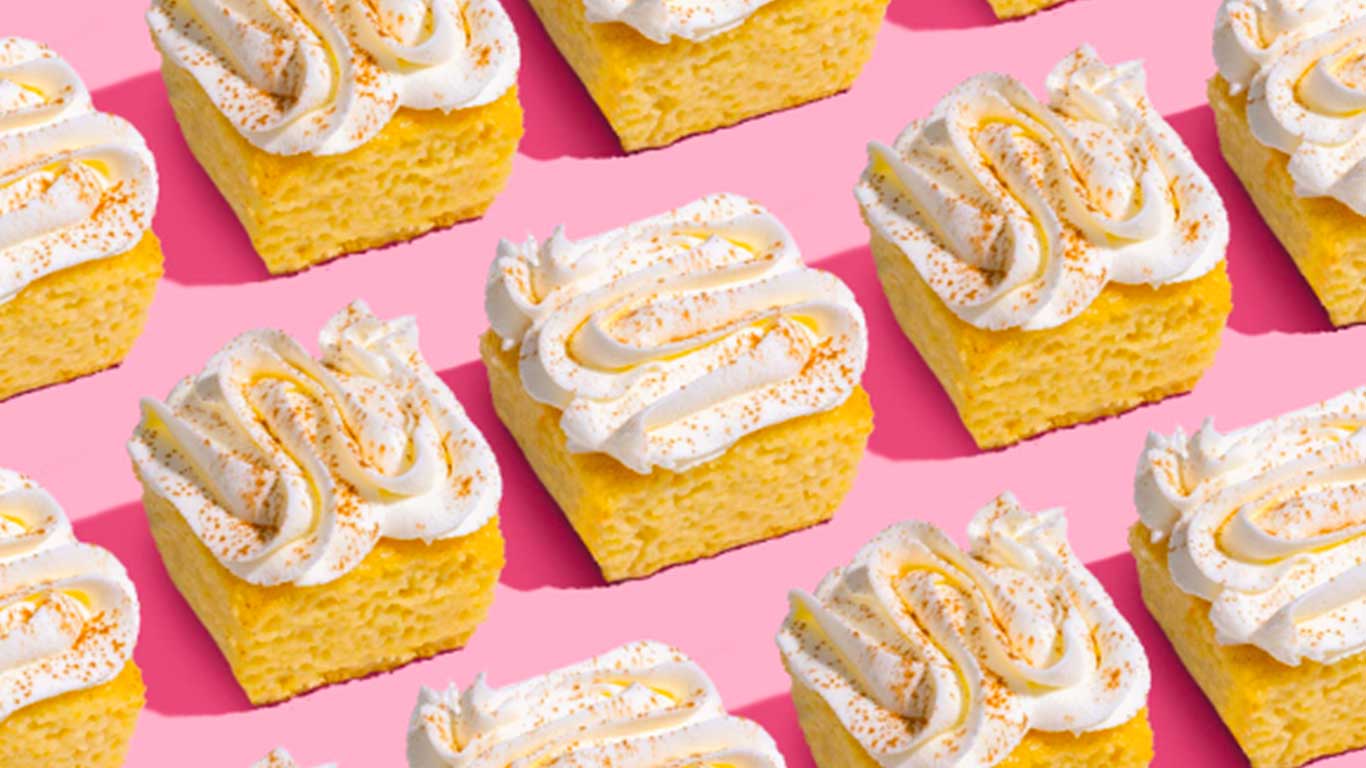 Rows of cookie bars with cinnamon frosting on top against a pink background