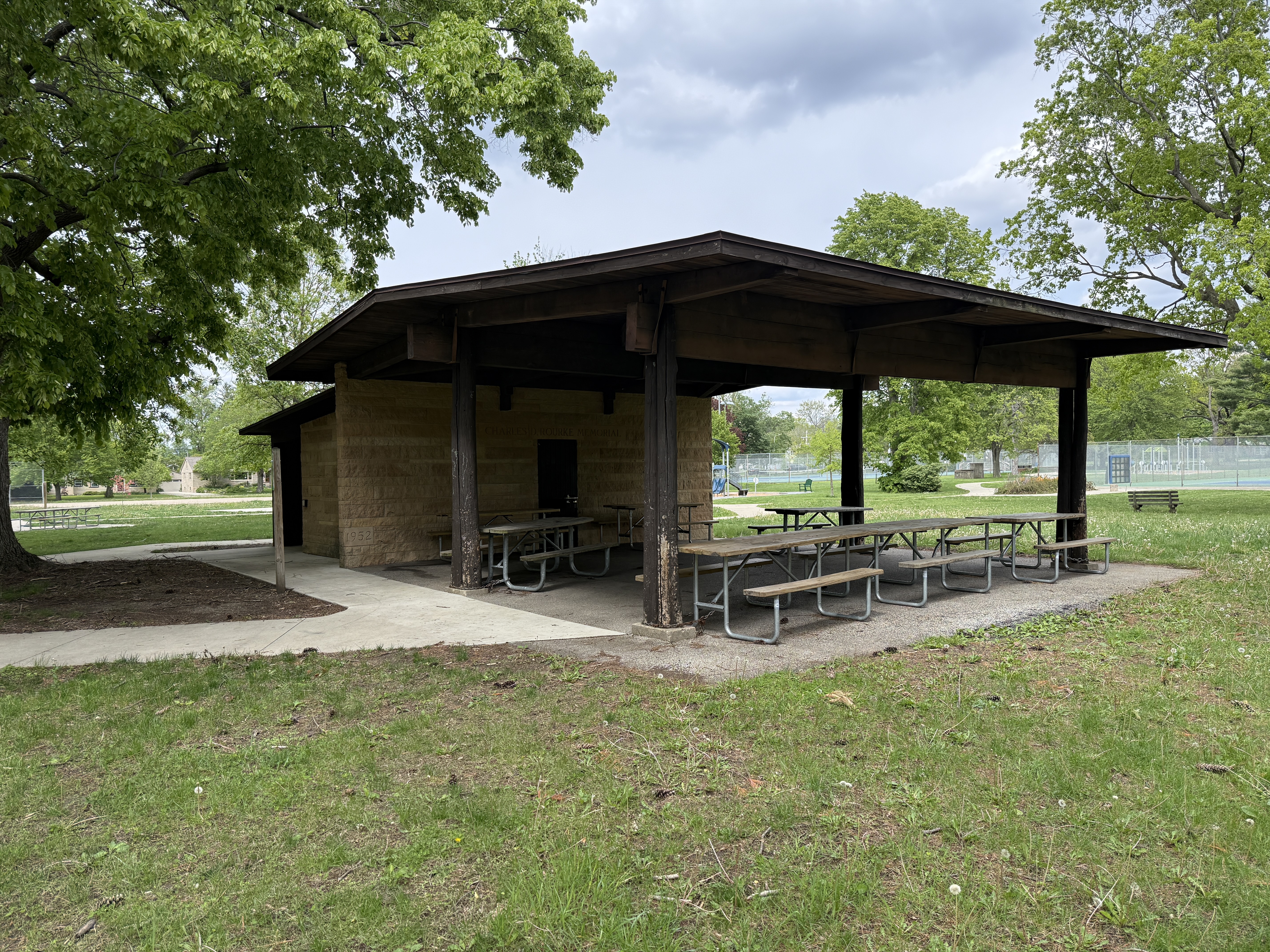 wood pavilion with picnic tables, surrounded by grass