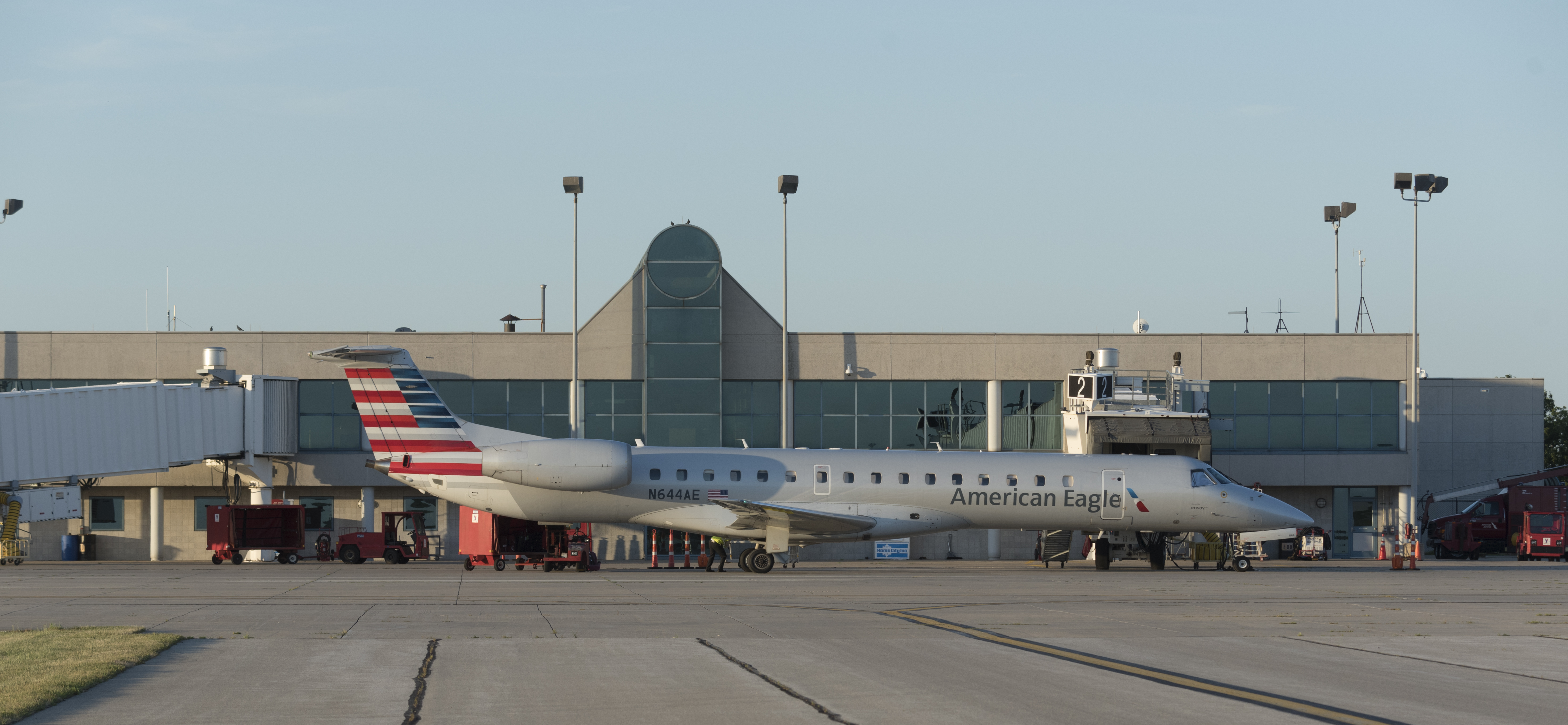 Exterior of a grey airport with many windows, behind a gray airplane