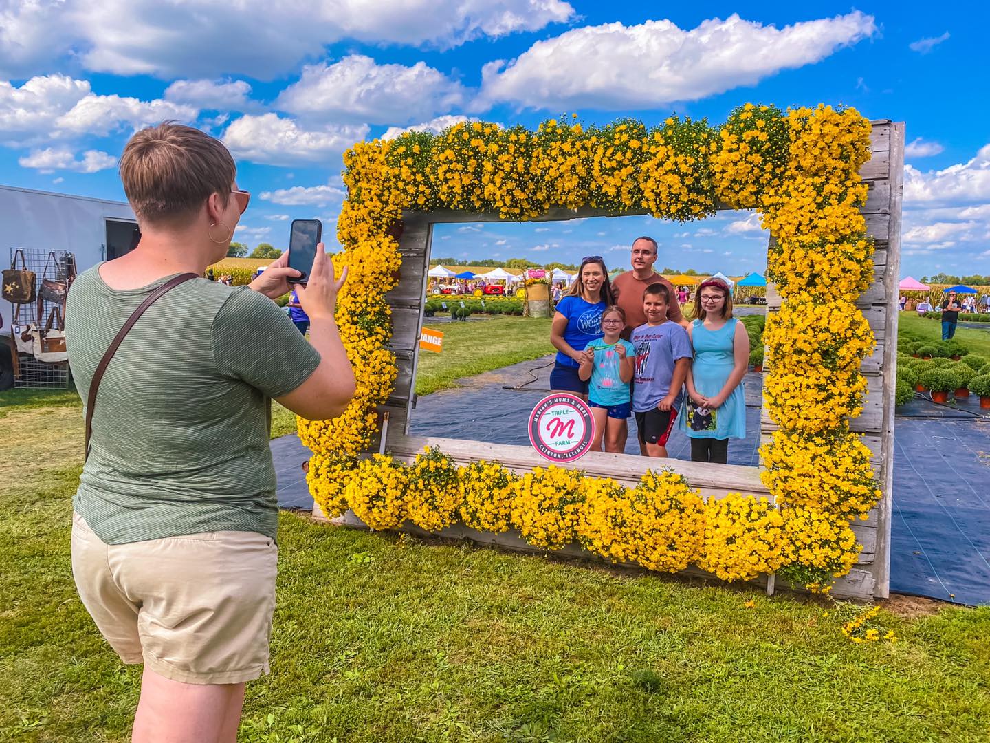Family taking a picture in a frame made of mums.