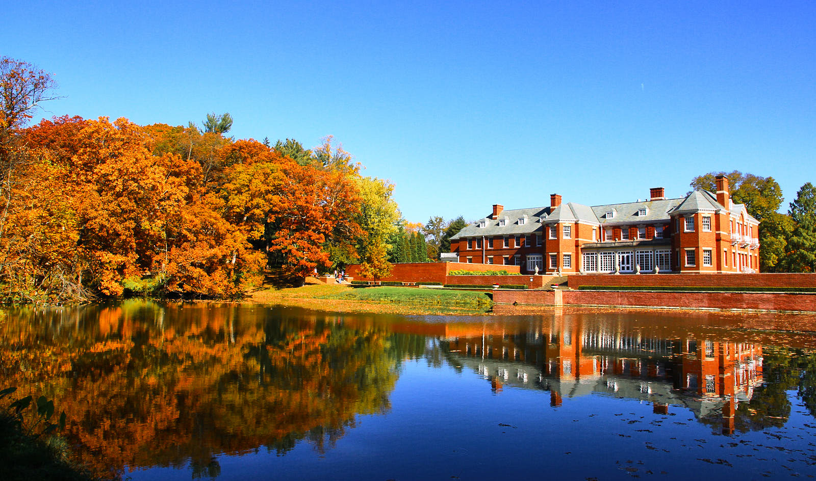 Pond, brick mansion, and forest in the fall