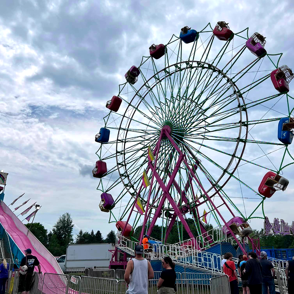 trumbull-county-fairgrounds-ferris-wheel-summer-carnival-ohio Colorful Ferris wheel at the Trumbull County Fairgrounds summer carnival in Northeast Ohio, with families lining up for rides.