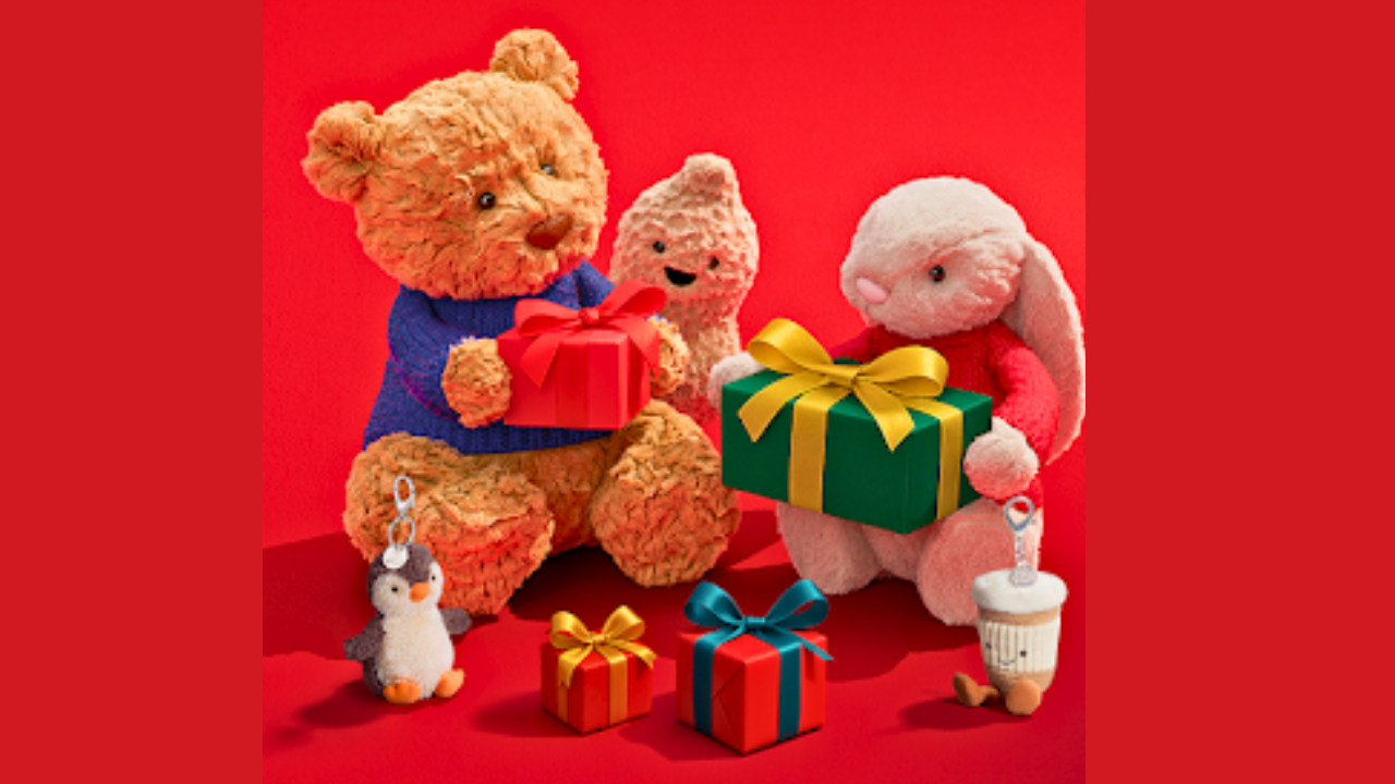 Plush teddy and bunny exchanging wrapped gifts on a red background - holiday gift ideas from Simpson Gallery & Gifts in Warren, Ohio.